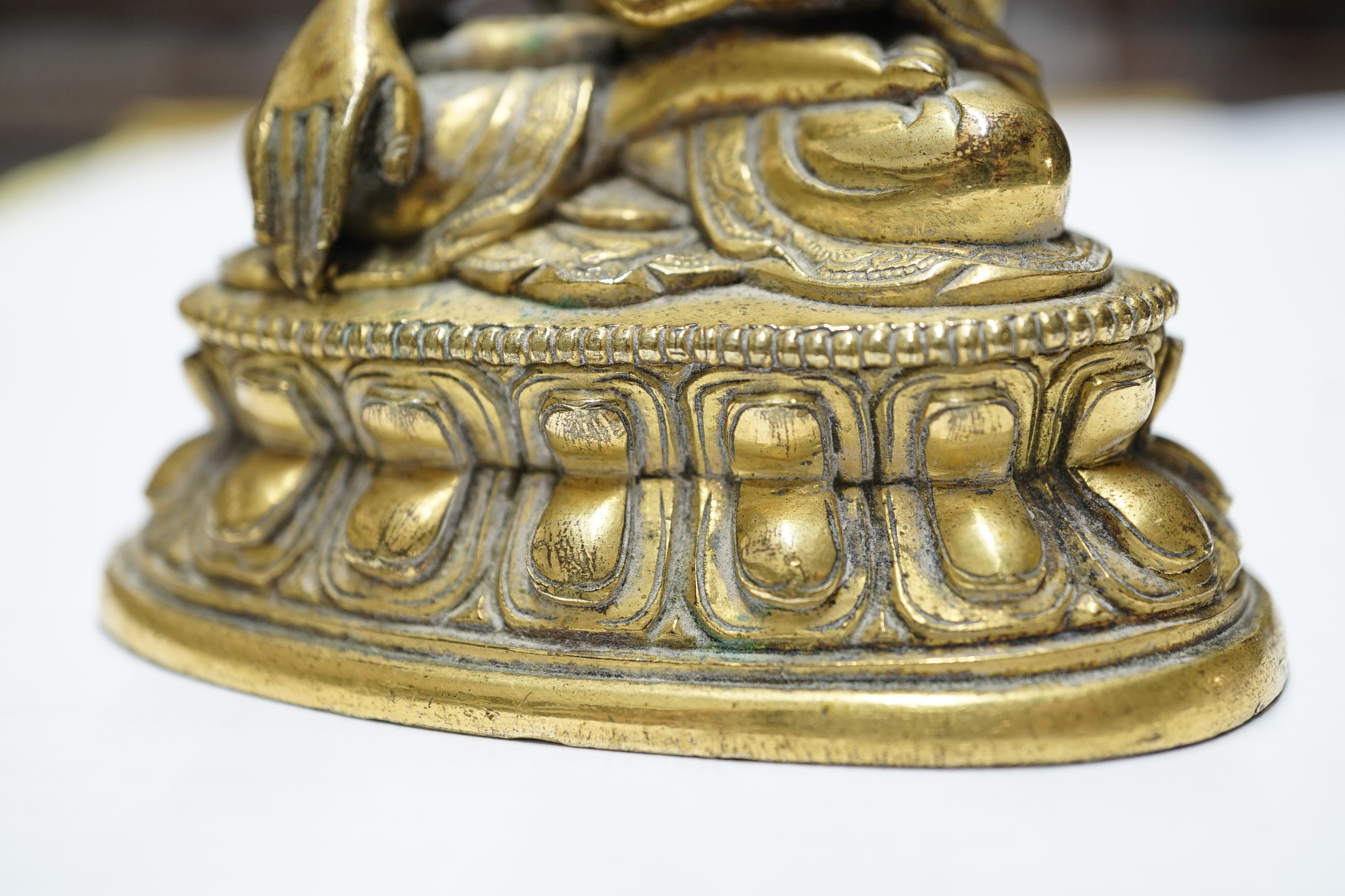 A small Tibetan gilt bronze seated figure of Buddha Shakyamuni, 18th century, 9.5cm high, lacking bowl in left hand